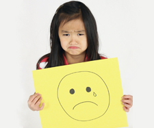 little girl holding a drawing of a sad face