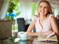 Cheerful girl with book sitting in cafe